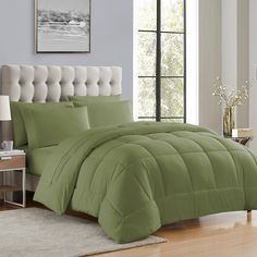 a bed with green comforter and pillows in a room