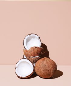 three whole coconuts sitting next to each other on top of a pink tablecloth