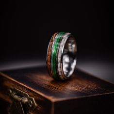 a wooden ring with green and white inlays sitting on top of a chest