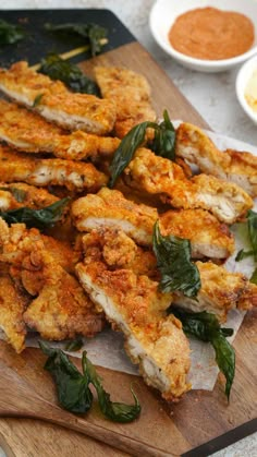 fried chicken on a cutting board with sauces in the background