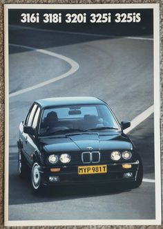 a black car driving down a road next to a white sign with the words bmw on it