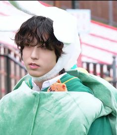 a young man wearing a green coat and white hat