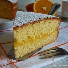 a slice of cake with powdered sugar on top and oranges in the background