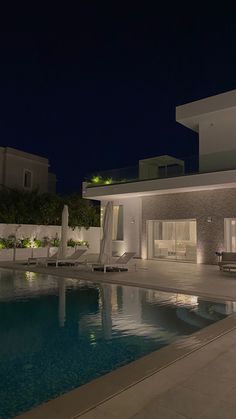 an empty swimming pool in front of a house at night