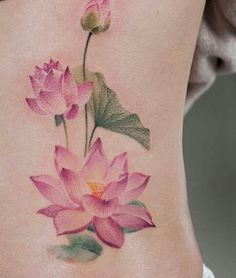 a woman's lower back tattoo with pink flowers and leaves on the side,