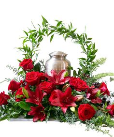 a vase filled with red flowers and greenery