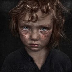 a young boy with freckled hair and blue eyes looks directly into the camera