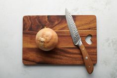 an onion on a cutting board next to a knife