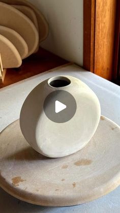 a white vase sitting on top of a plate