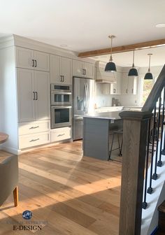 an open kitchen with white cabinets and wood flooring is pictured in this image from the stairs leading up to the upper level