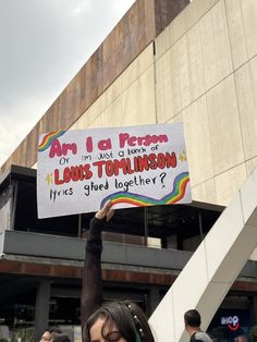 a woman holding up a sign that says, are i a person or just a bunch of louis tom linson?