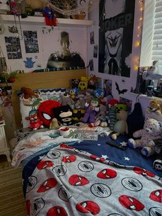 a bedroom with spiderman bedding and stuffed animals on the bedspread in it