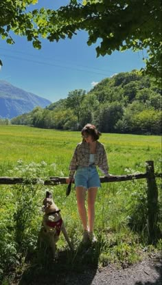 a woman standing next to a dog on a lush green field