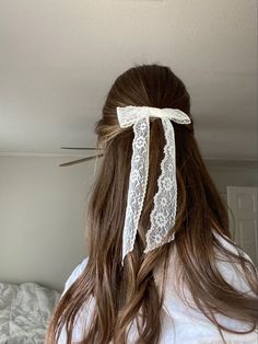 the back of a woman's head with long hair tied in a bow and white lace