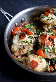 a pan filled with chicken and tomatoes on top of a table