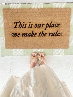 a person standing in front of a door mat that says, this is our place we make the rules