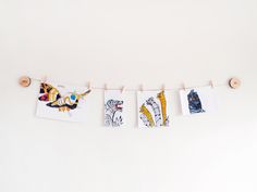 three pictures hanging on clothes pins with clothes pins attached to them, and some drawings hung up in front of them