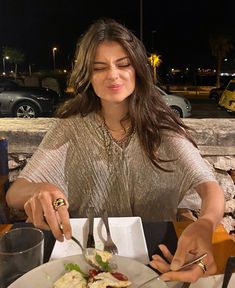 a woman sitting at a table with a plate of food in front of her,