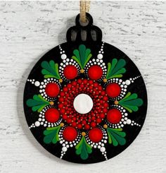 an ornament is hanging on the wall with red berries and leaves painted on it