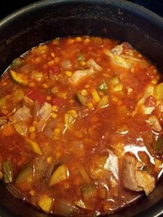 a pot filled with soup and vegetables on top of a stovetop burner, ready to be cooked