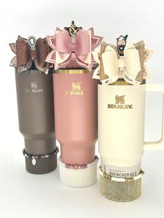 three different colored coffee mugs with bows on the top one is pink, brown and white