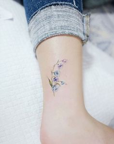 a small tattoo on the ankle of a woman's foot with flowers in it