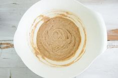 a white bowl filled with brown liquid on top of a wooden table