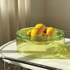 three lemons in a glass bowl on a table