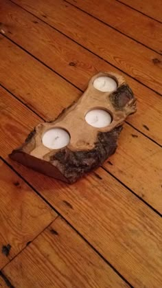 three candles are placed in a piece of driftwood on the floor with wood planks