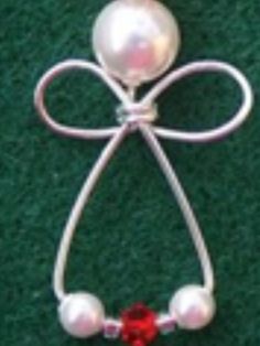 a brooch with pearls and a red bead hanging from it's side