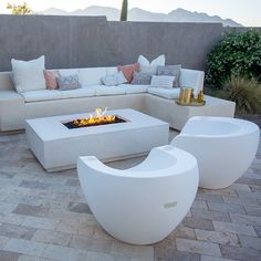 an outdoor fire pit surrounded by white furniture