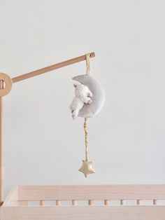 a baby crib with a white teddy bear hanging from it's side, next to a wooden pole