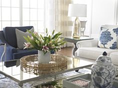 a living room filled with furniture and a glass coffee table in front of a window