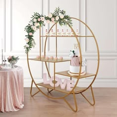 two tiered cake stand with pink and white flowers on top, one holding a love sign