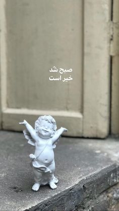 a small white angel figurine sitting on top of a cement step next to a door