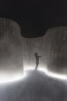 a person standing in the middle of a tunnel with light coming from it's walls