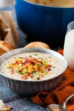 a bowl of soup sitting on top of a table next to a glass of milk