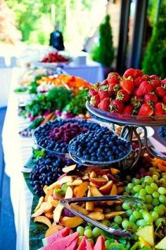 an assortment of fruits and vegetables displayed on a buffet table at a wedding or party