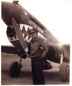 a man standing in front of an airplane with a shark face on it's side