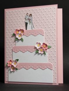 a wedding card with pink and white flowers on the bottom, two tiered cake