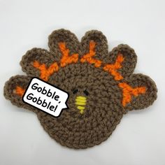 a crocheted turkey with an orange beak and the words gobble gobble on it