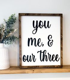 a wooden sign that says you me and our three on it next to a vase with flowers