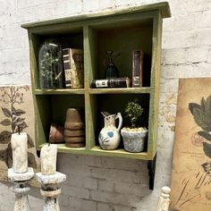 an old shelf with pots, vases and other items on it in front of a brick wall