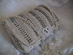 a crocheted purse sitting on top of a white bed covered in lacy fabric