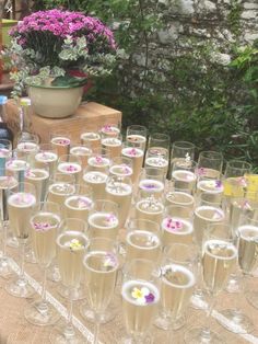 there are many wine glasses on the table with flowers in them and one is empty