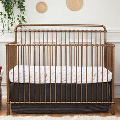 a baby crib in a white room with plants on the wall and rugs