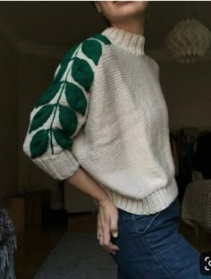 a woman wearing a white sweater with green leaves on it