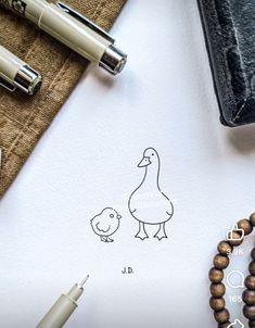 a paper with a drawing of a duck and a chick on it next to some pens