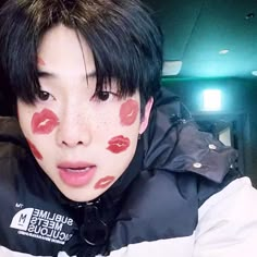 a man with red lipstick on his face and black hair wearing a puffy jacket