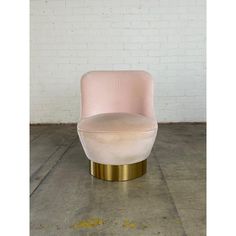 a pink chair sitting on top of a cement floor next to a white brick wall